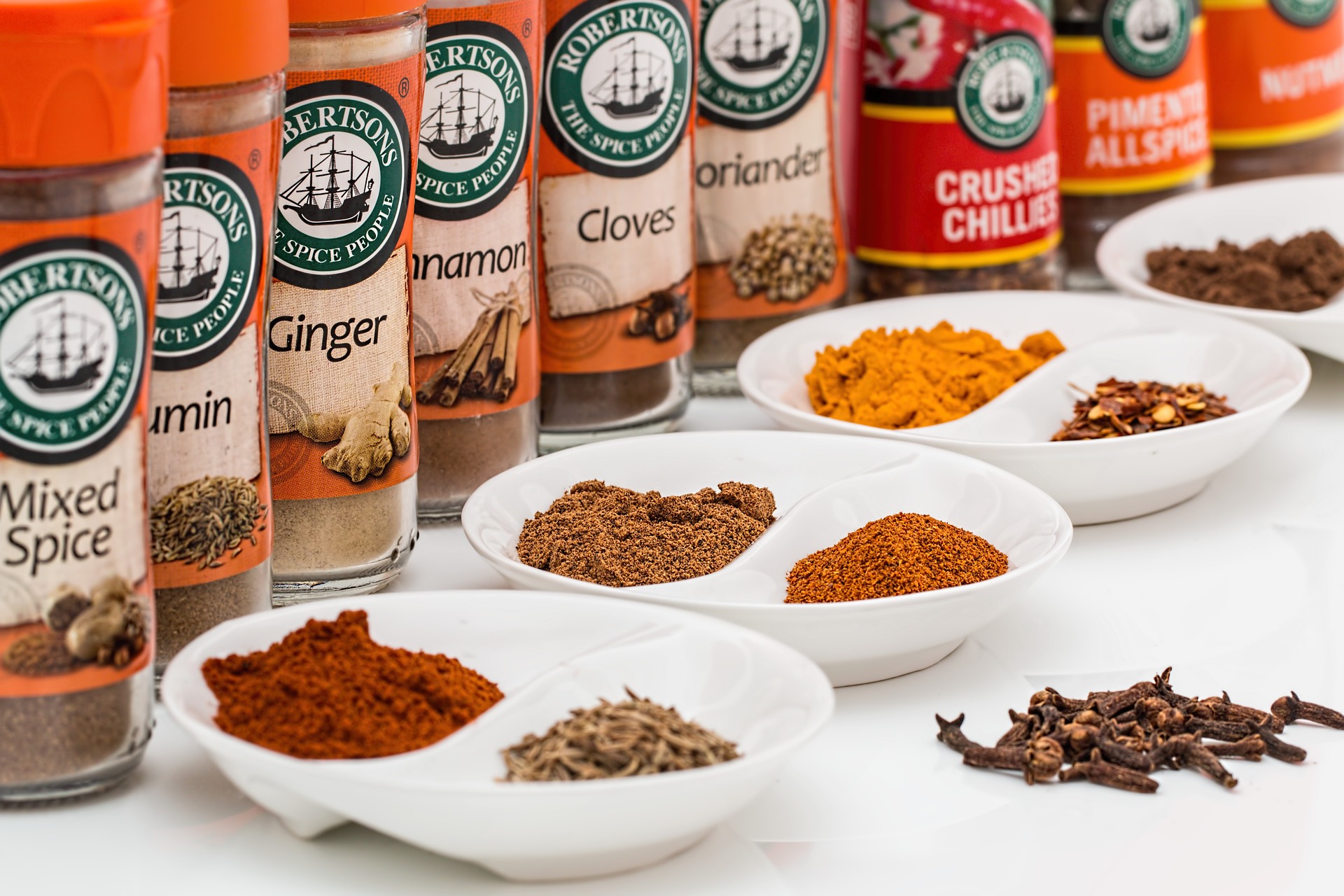 A row of spices (ginger, cloves, crushed chili pepper, etc.)